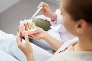 Photo of a woman holding dental implants on a teeth model