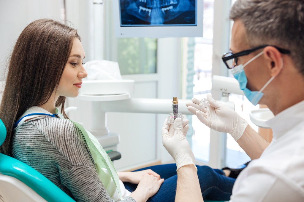 oral surgeon showing patient dental implant